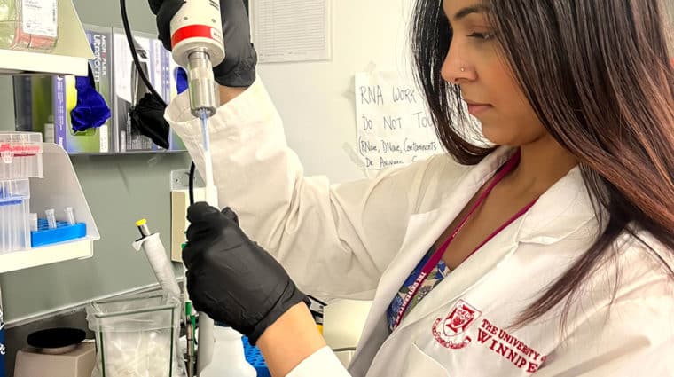 A person is working in lab wearing white lab coat and black gloves.