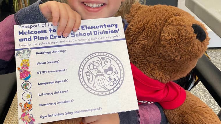 Child sitting on chair and holding certificate.