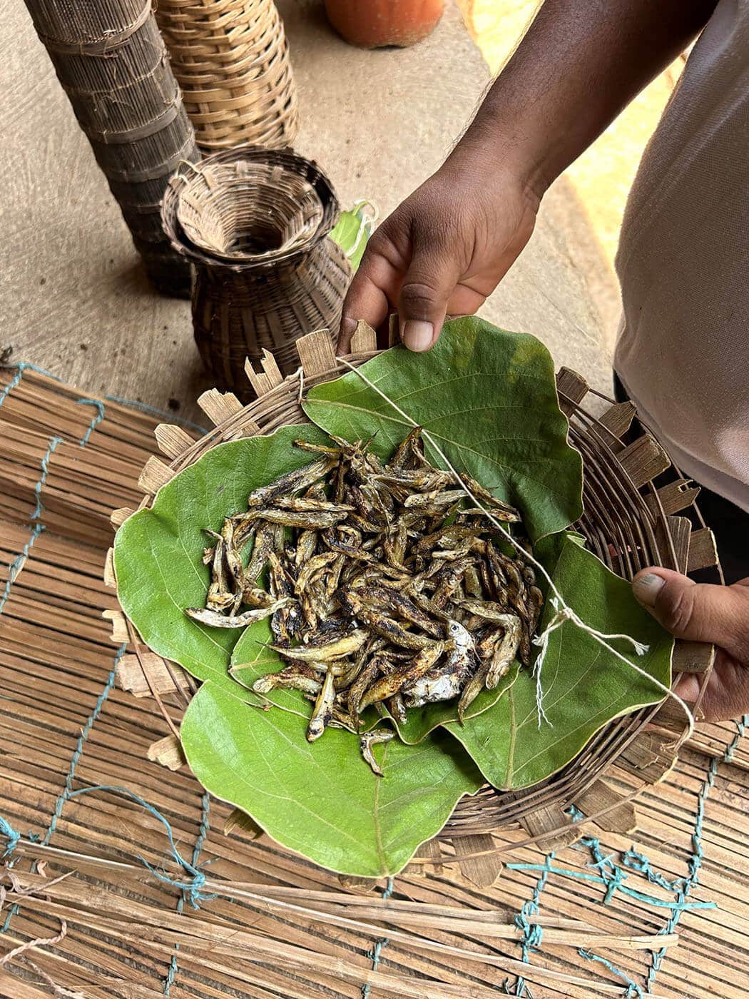 Photo of a small bamboo basket with dried fish in it.