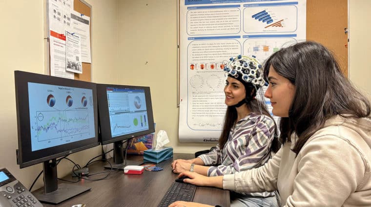 Researcher records EEG data as a participant views emotional stimuli, analyzing brain activity to study emotion recognition and regulation.