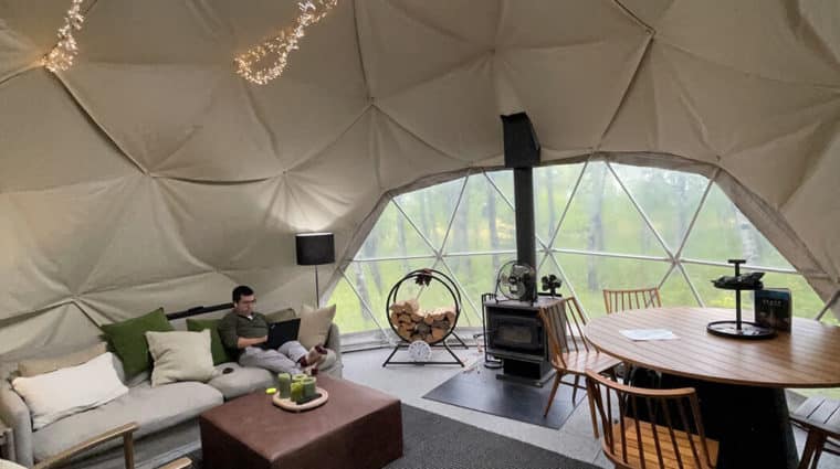 A researcher focuses on his writing in a forest dome during a research retreat.