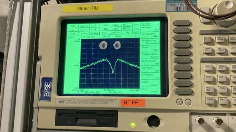 A parabolic dip is shown on a screen on an electronic device. Many others like it along with wires fill the background.
