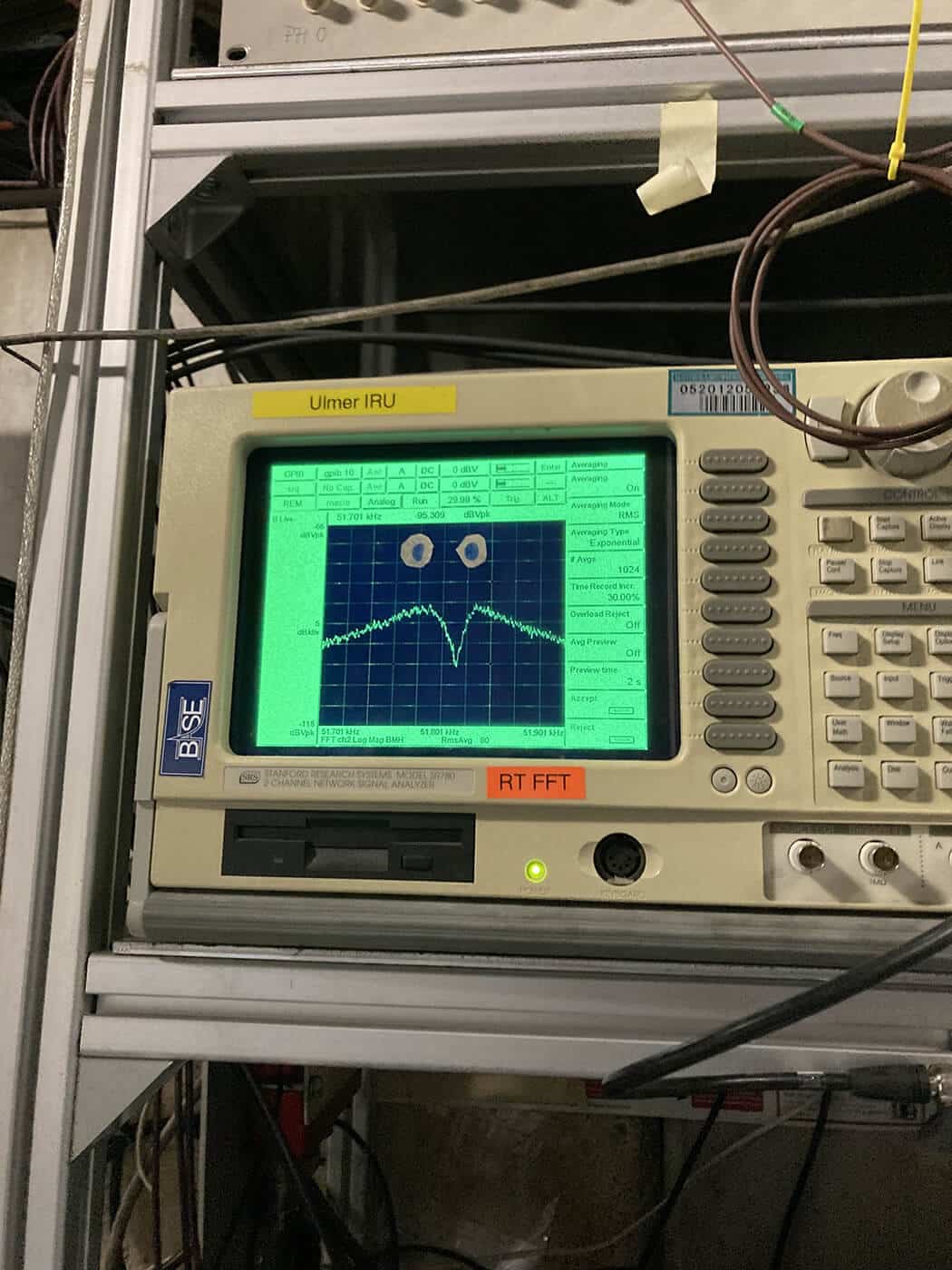 A parabolic dip is shown on a screen on an electronic device. Many others like it along with wires fill the background.