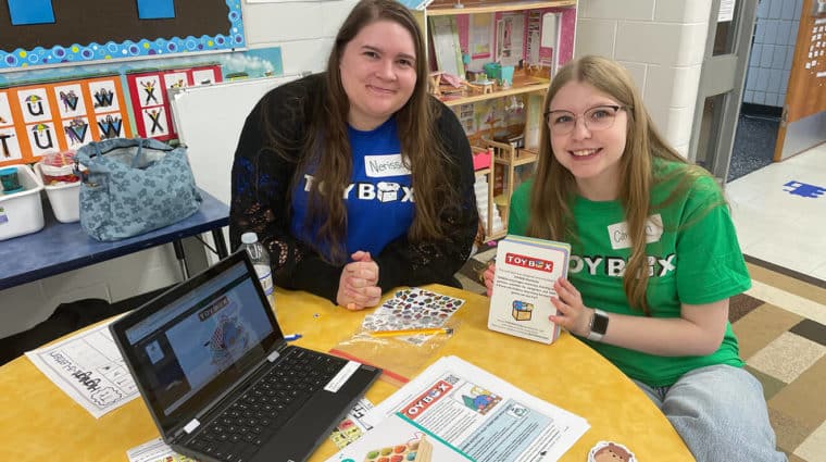 Researchers in a boat next to a yellow net in the water. The red and green northern lights are in the sky.
