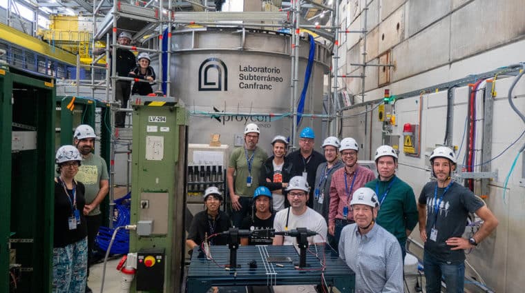 The large metal tank behind the researchers in the photo holds the water that is viewed by 100 photosensors and eight photogrammetry cameras.